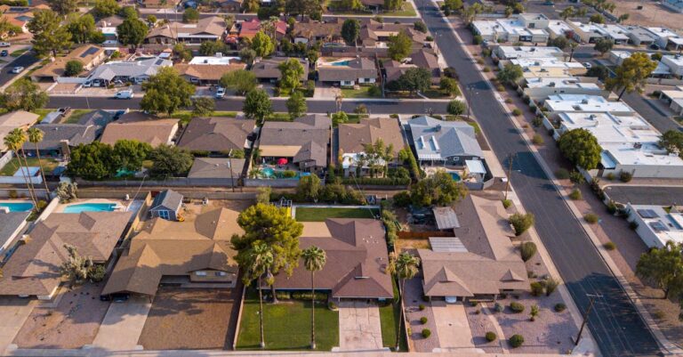 Drone shot of a suburban neighborhood showcasing houses, roads, and lush greenery.
